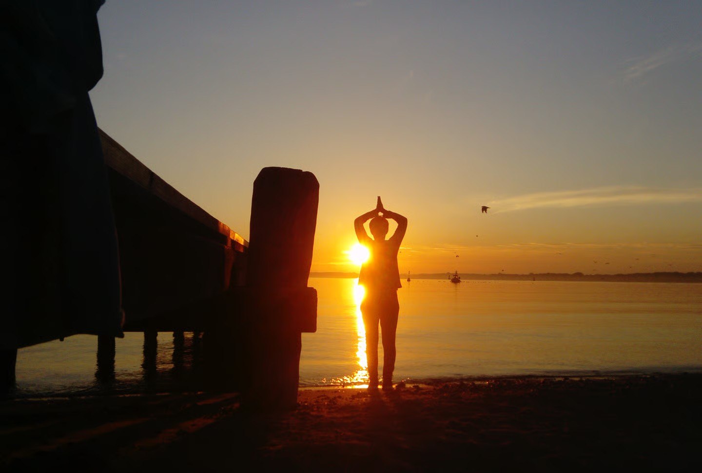 Yoga-Sonnengruß im Sonnenaufgang am Wasser